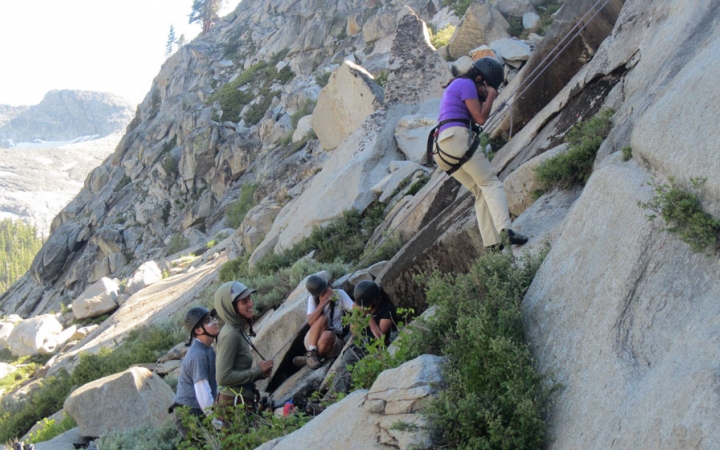 a group of students laugh as they rock climb on an outward bound course for bipoc